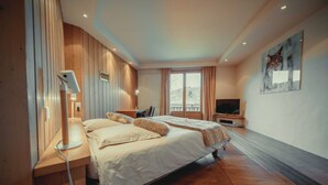 A modern hotel room with a large bed, a desk, a TV, and a view of the outdoors.