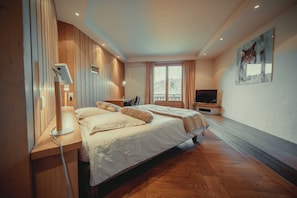 Camera d'albergo moderna con un ampio letto, una scrivania, una televisione e vista sull'esterno.