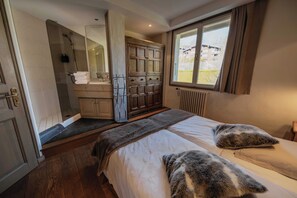 Quarto com cama grande, armário de madeira, banheiro com chuveiro e janela com vista.