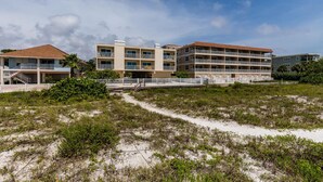 A beachfront hotel with multiple floors, a sandy beach in front, and a clear sky. - Marquise 204 Beachfront 2br, 2 Bath condo-Directly on Beach! (Indian Rocks Beach)