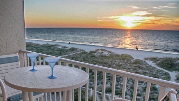 A balcony with a view of the beach and ocean at sunset. - Marquise 204 Beachfront 2br, 2 Bath condo-Directly on Beach! (Indian Rocks Beach)