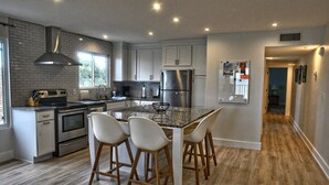 A modern kitchen with a central island, stainless steel appliances, and a wood floor. - Marquise 204 Beachfront 2br, 2 Bath condo-Directly on Beach! (Indian Rocks Beach)