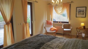 A bedroom with a bed, a chair, a table with a lamp, a window with curtains, and a chandelier. - *** Star apartment, large terrace on the south slope with panoramic views near the Rursee  (Simmerath)