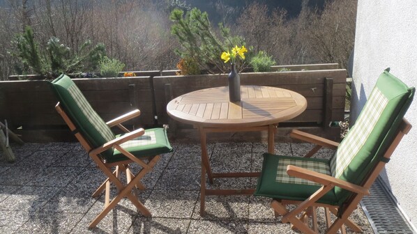 A patio with two green cushioned chairs and a wooden table with a vase of yellow flowers. - *** Star apartment, large terrace on the south slope with panoramic views near the Rursee (Simmerath)