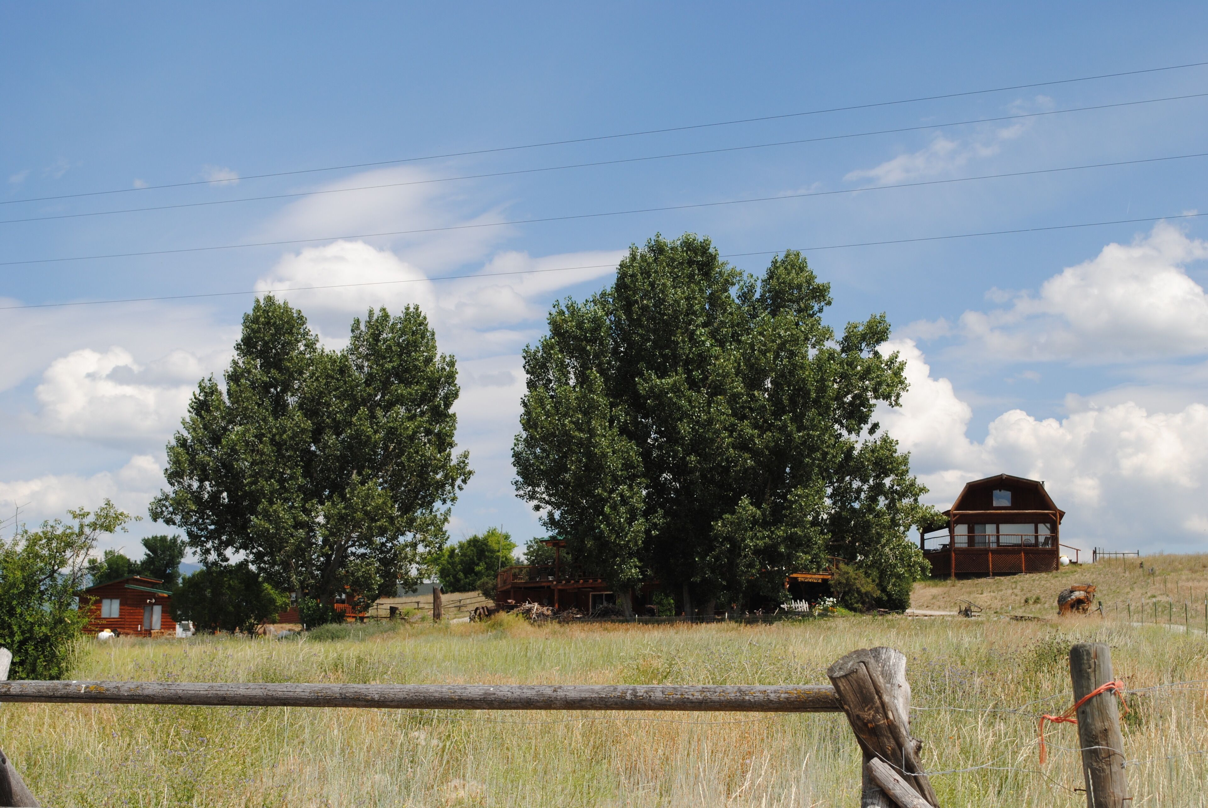 A rural landscape with a wooden cabin and a larger wooden structure on a hill.
