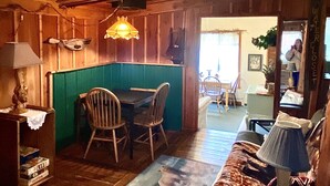 A cozy cabin interior with a dining area, a sofa, and a mirror reflecting the room. - Wilderness Spirit Cabins 'Bear Cave' cabin-family friendly/sportsman paradise (Corvallis)