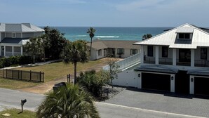 A residential area with a view of the ocean, featuring houses with a garage and a small driveway.