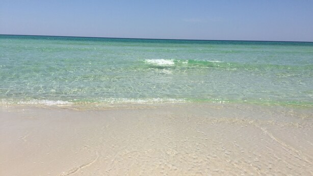 A beach with clear turquoise water and a sandy shore.