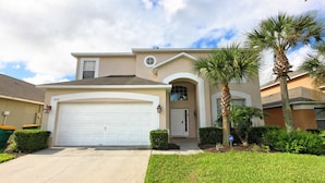 A two-story house with a white garage door, a small front porch, and a well-maintained lawn.