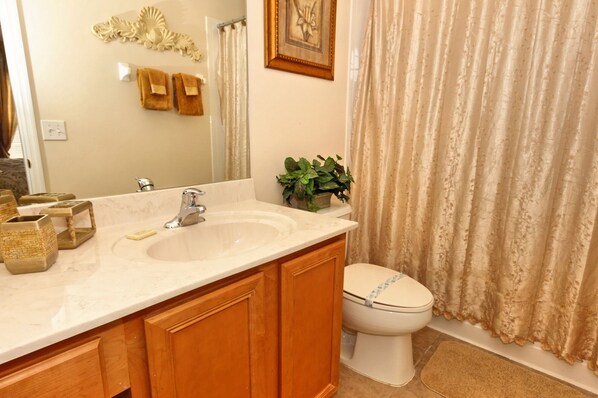 A bathroom with a sink, mirror, towel rack, toilet, and shower curtain.