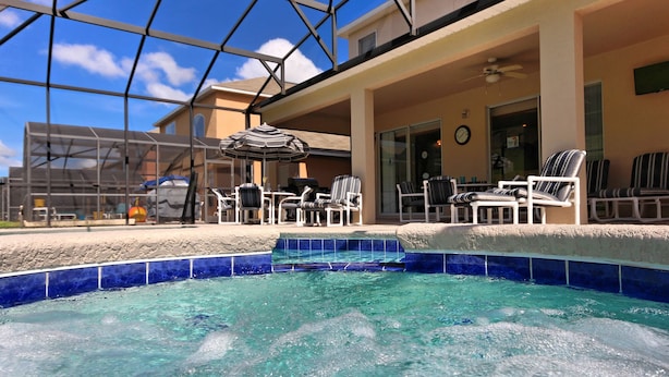 An indoor pool area with clear blue water, surrounded by lounge chairs and umbrellas.