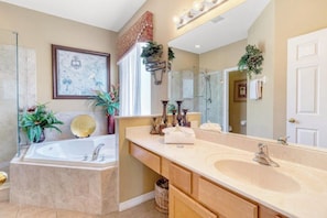 Un baño con bañera, un lavabo grande con pileta, un espejo y plantas decorativas.