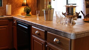 A kitchen with wooden cabinets, a built-in dishwasher, a countertop with a potted plant, a candle, and a decorative pot. - Charming Chalet - Walk to Whiskey Row! Dog friendly (Prescott)
