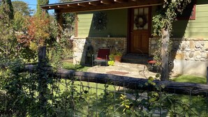 A house with a stone foundation, a wooden porch, and a green exterior wall.