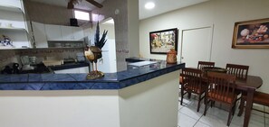 A kitchen with a marble countertop, wooden chairs, and a dining table. - Departamentos en Manta (Manta)