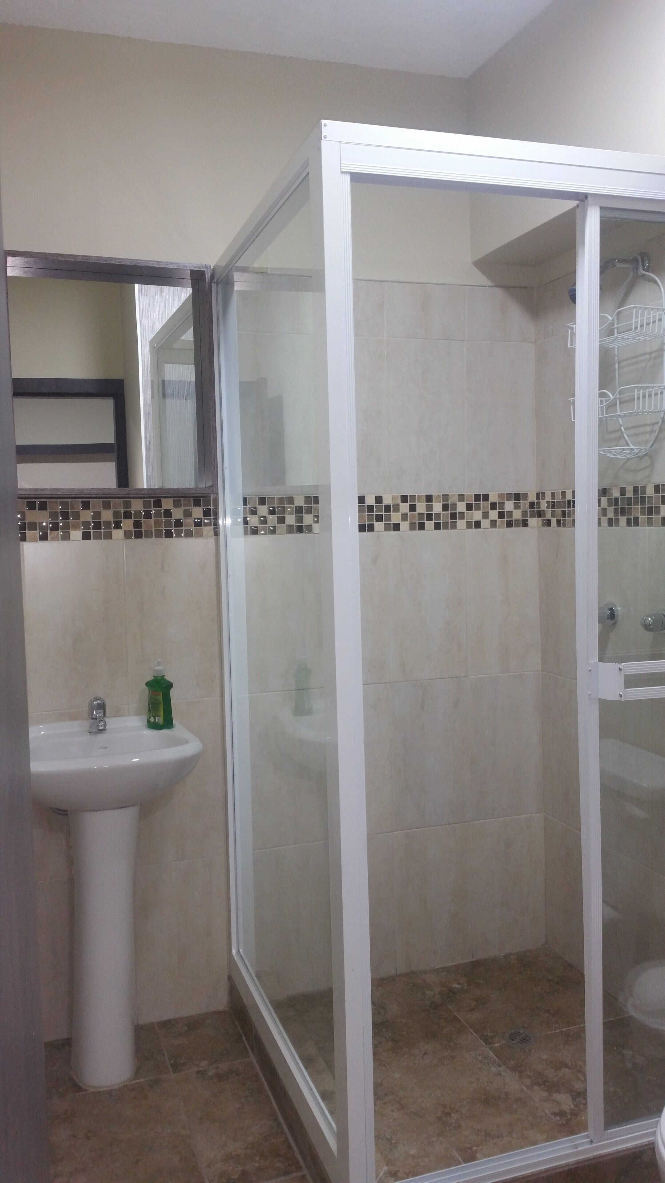 Un bagno con cabina doccia, lavandino e specchio.