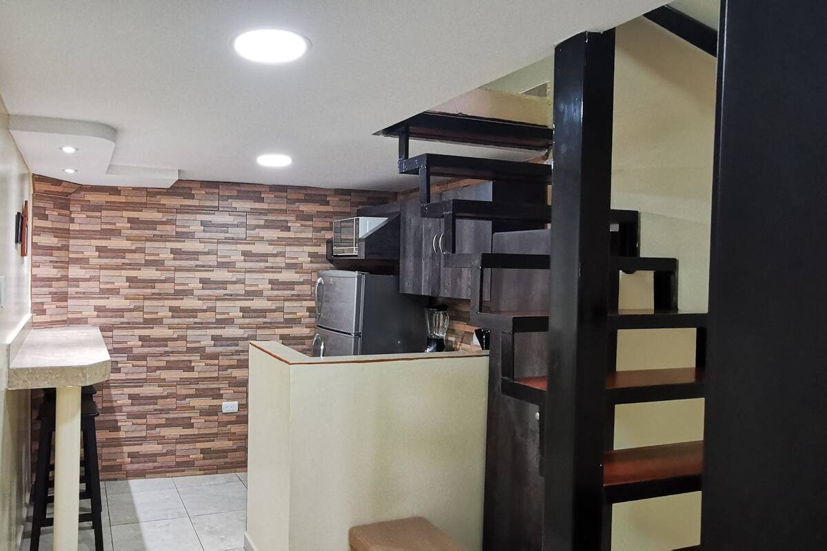 A compact kitchen with a modern design, featuring a built-in oven, a microwave, and a coffee machine.