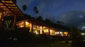 A large, open-air structure with multiple rooms, surrounded by tropical vegetation and palm trees. - Fare Oviri Lodge (Raiatea)