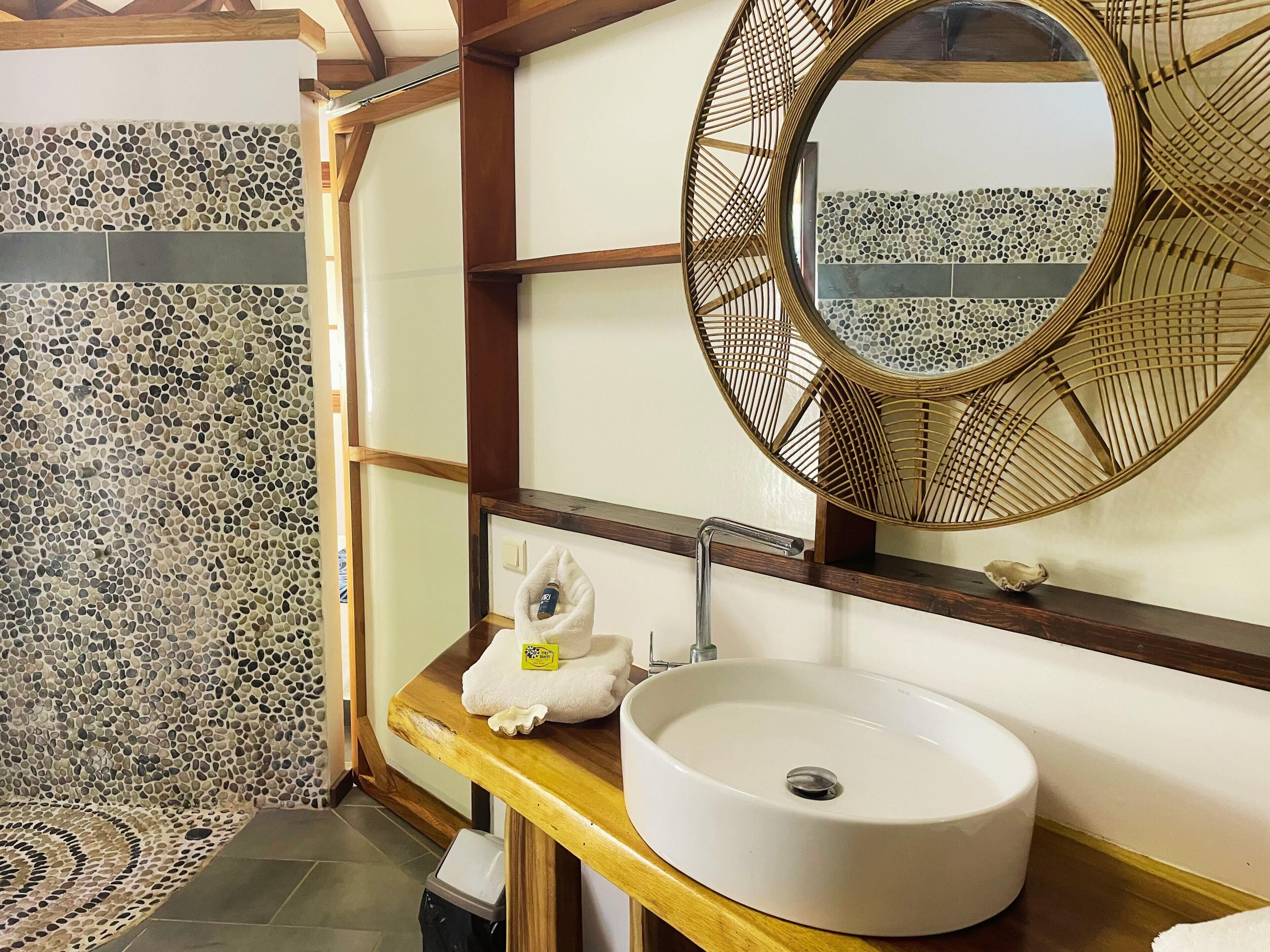 A bathroom with a round mirror, white sink, and a towel rack.