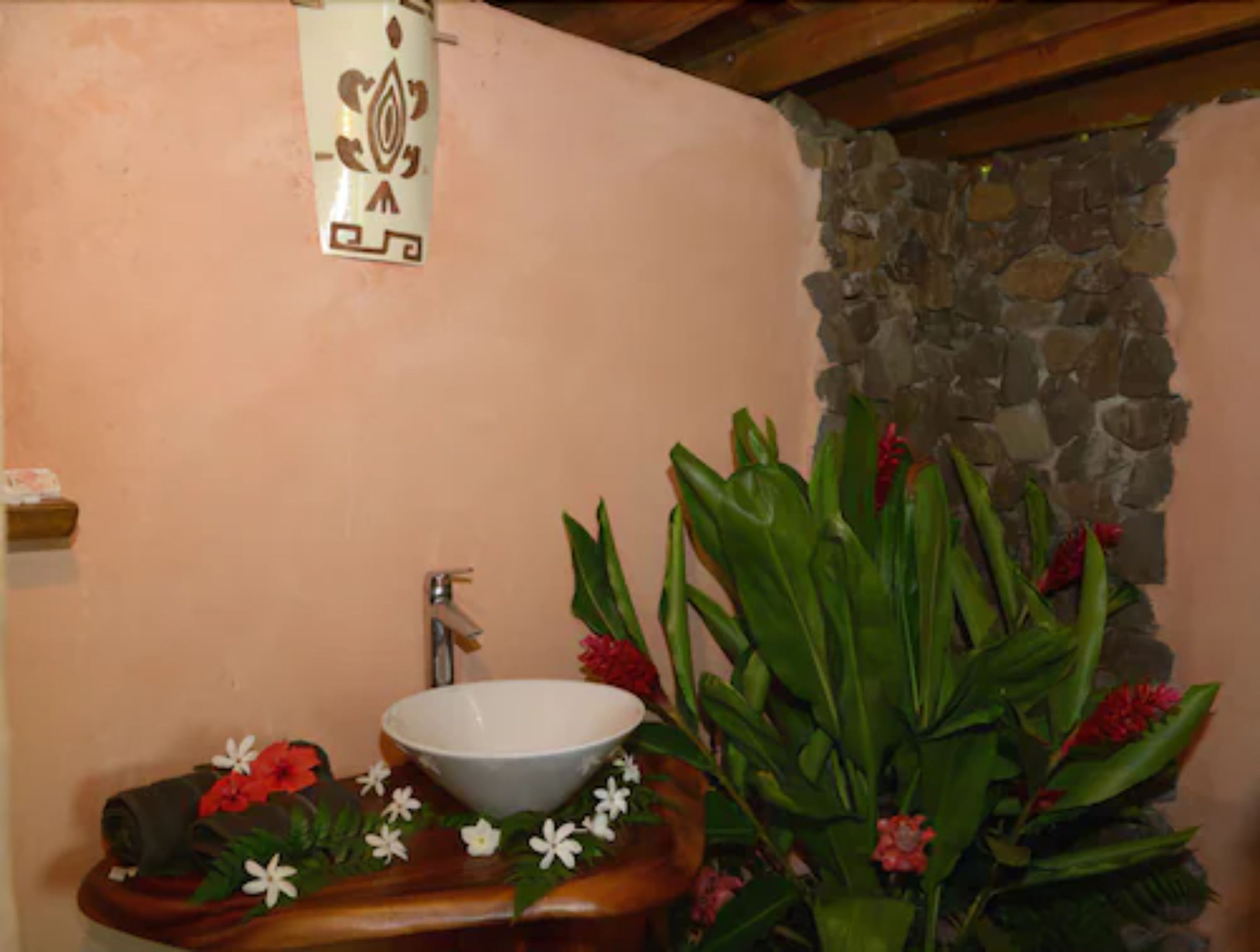 A bathroom with a stone wall, a sink with a white basin, and a wooden countertop.
