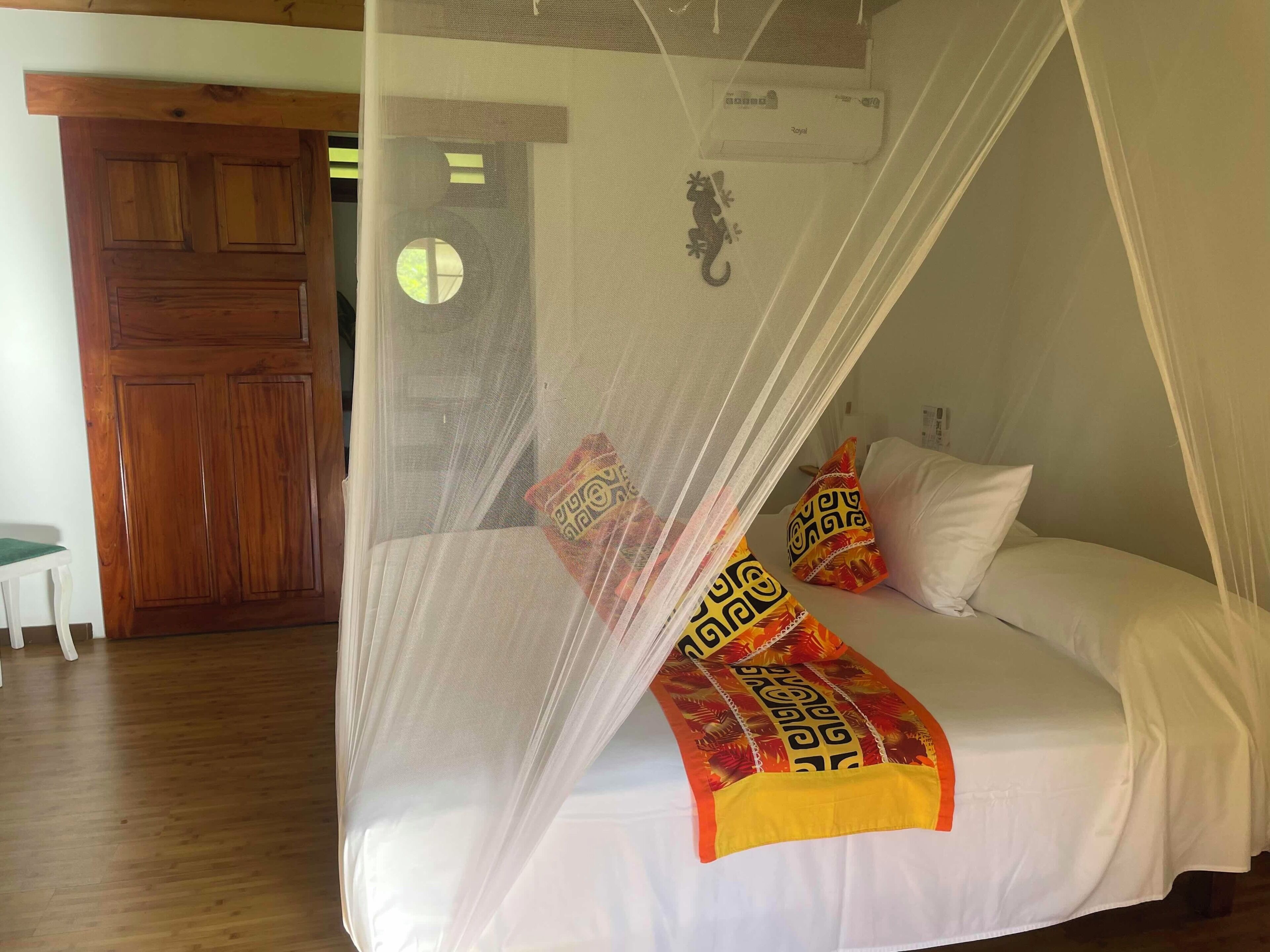 A bed with a mosquito net, pillows, and a blanket.