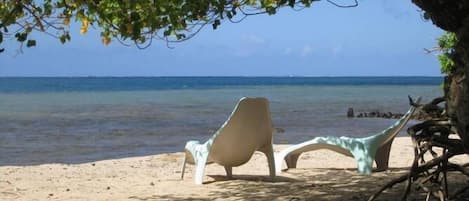 Een privéstrand, wit zand, ligstoelen aan het strand, kajakken