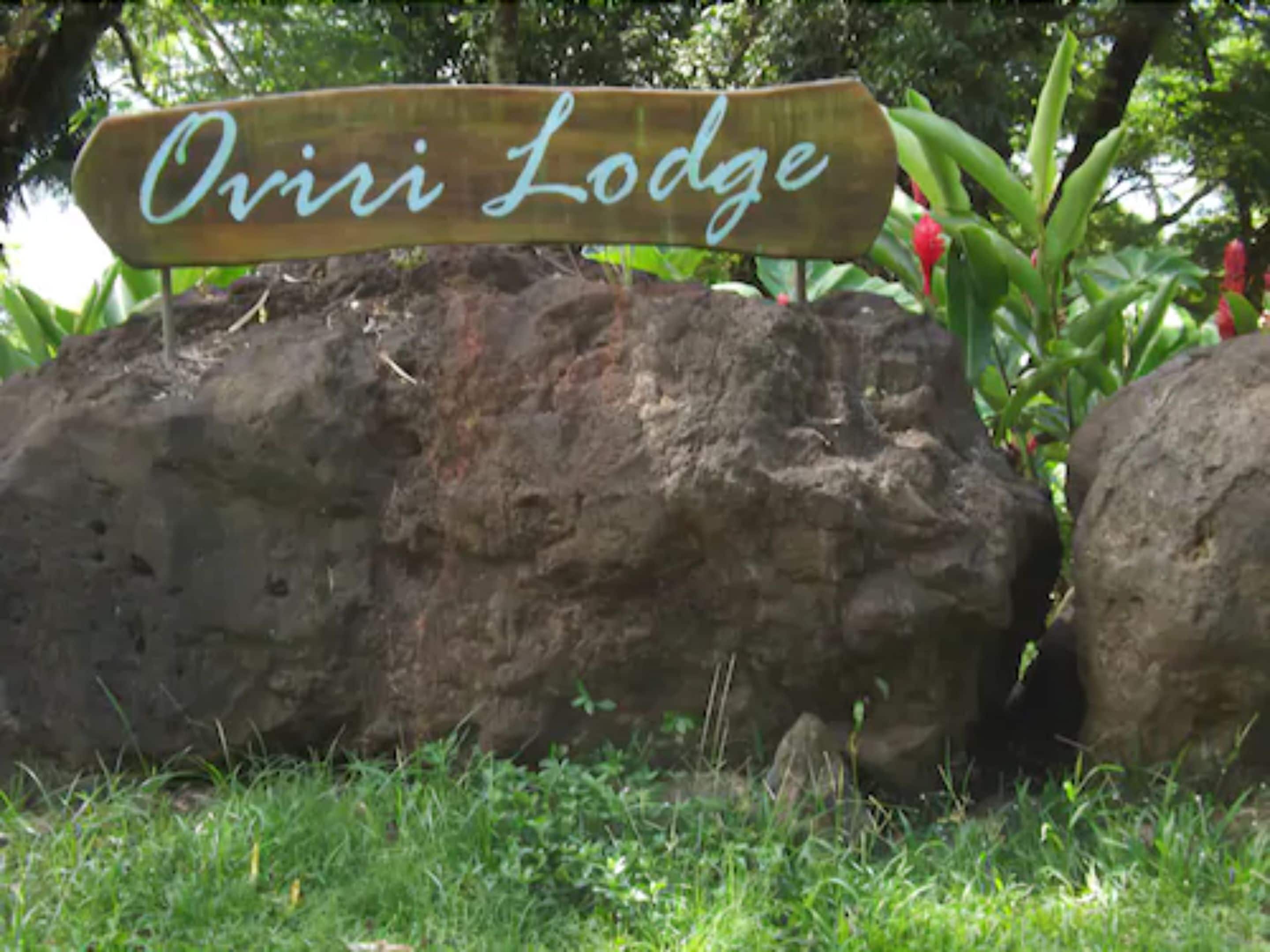 Une pancarte en bois portant l’inscription « Oviri Lodge » est fixée sur un rocher.