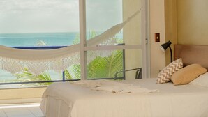 A bedroom with a bed, a hammock, and a view of the ocean. - Pousada Garatéia (Bombinhas)