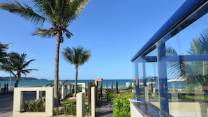 A modern building with large glass windows overlooking a beach. - Pousada Garatéia (Bombinhas)