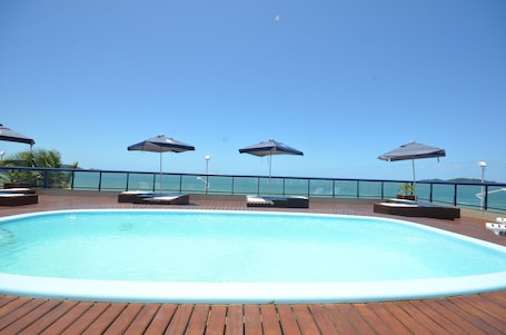 Una piscina al aire libre, sillones reclinables de piscina