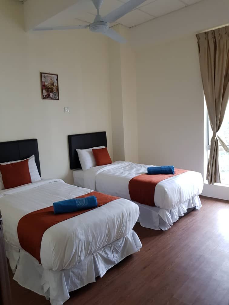 Une chambre d’hôtel avec deux lits, un ventilateur de plafond, une fenêtre avec des rideaux et un tableau accroché au mur.