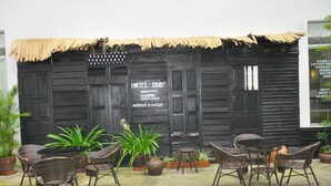 Un espacio de estar al aire libre de estilo rústico con sillas y mesas de mimbre, techo de paja y un letrero de Hotel Double Stars.