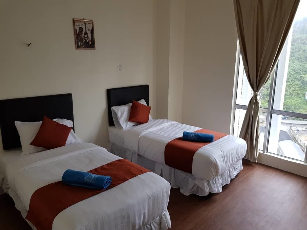 Two single beds with white and red bedding, a framed picture on the wall, and a large window with curtains.