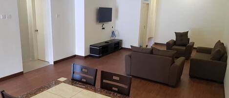 Amplia sala de estar con mesa de comedor, sillas, sofás y un televisor de pantalla plana montado en la pared.