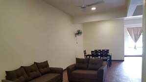 Una sala de estar con dos sofás, una mesa de comedor con sillas, un ventilador de techo y un ventanal grande.