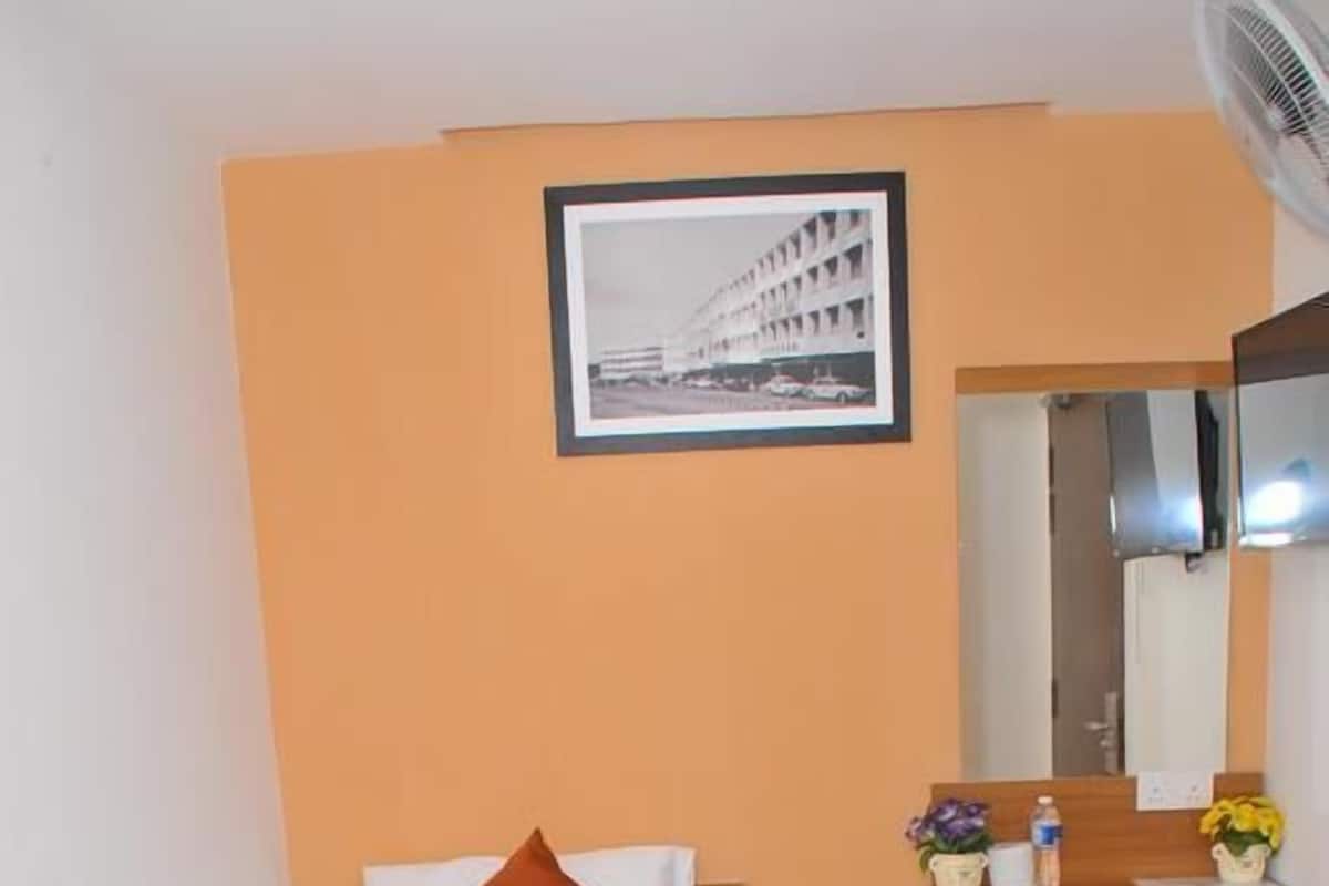 Une chambre d’hôtel avec un lit, un bureau en bois, un miroir et un tableau accroché au mur.
