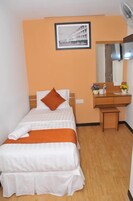 Una camera d'albergo con un letto, una scrivania in legno, uno specchio e un quadro appeso al muro.