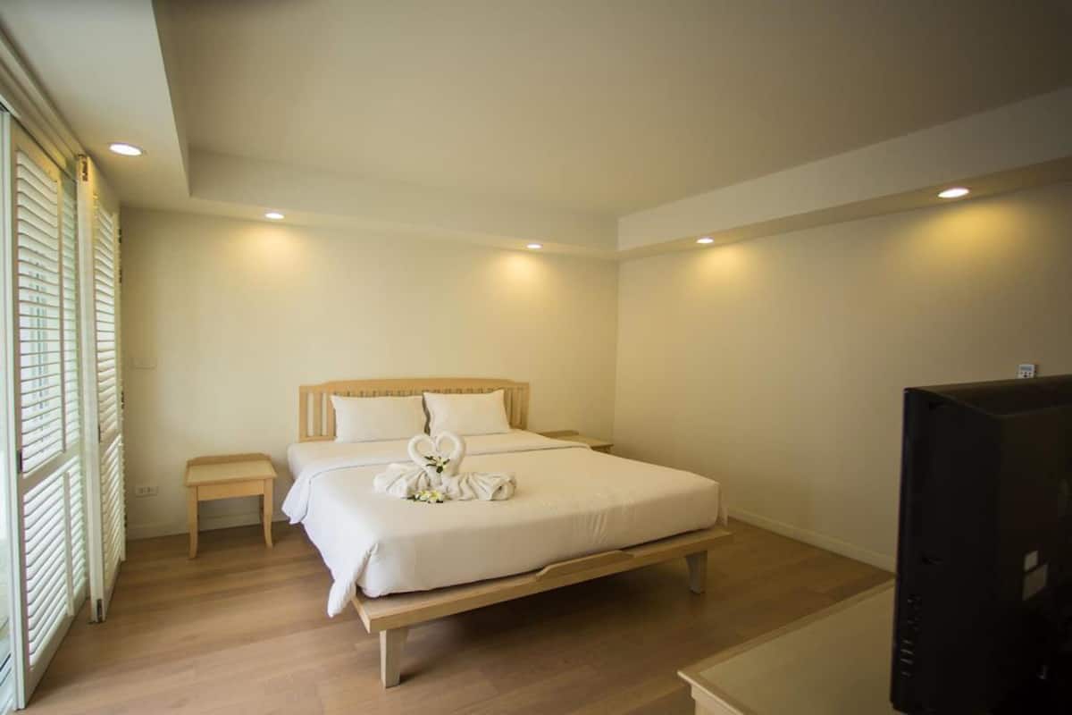 Habitación de hotel con una cama individual, mesita de noche y televisión.