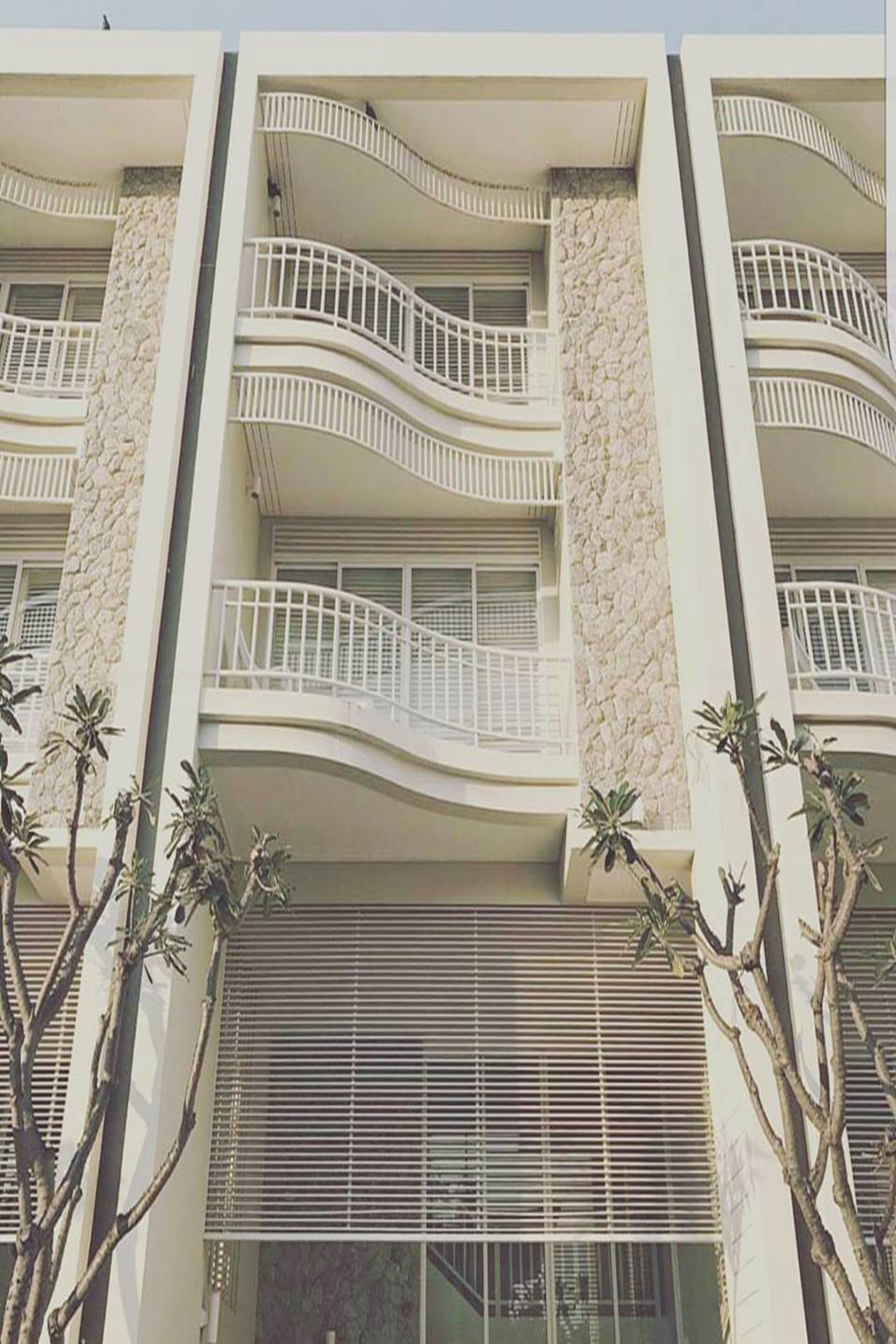 Um edifício de vários andares com varandas, janelas amplas e fachada de pedra.