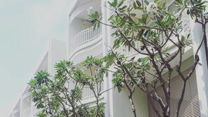 A row of white buildings with balconies and trees in front. - Baan Sea Talay (Cha-am)
