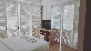 A bedroom with a bed, a TV, and a wardrobe with sliding doors. - Baan Sea Talay (Cha-am)
