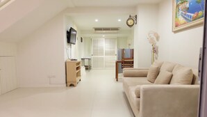 A spacious living room with a beige sofa, a television mounted on the wall, and a painting on the wall. - Baan Sea Talay (Cha-am)
