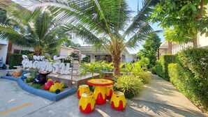 A courtyard with palm trees, a pool, and outdoor seating. - Baanloksouylokchay (Hua Hin)