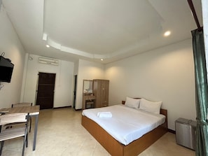A hotel room with a bed, a desk, a wardrobe, and a TV.