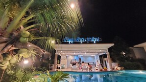 A hotel with a pool area, palm trees, and a sign with Thai script. - Baanloksouylokchay (Hua Hin)