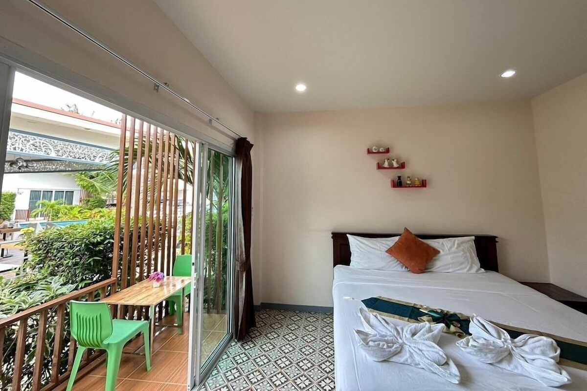 Une chambre d’hôtel avec un lit, une petite table, deux chaises, un balcon avec vue et une fenêtre.