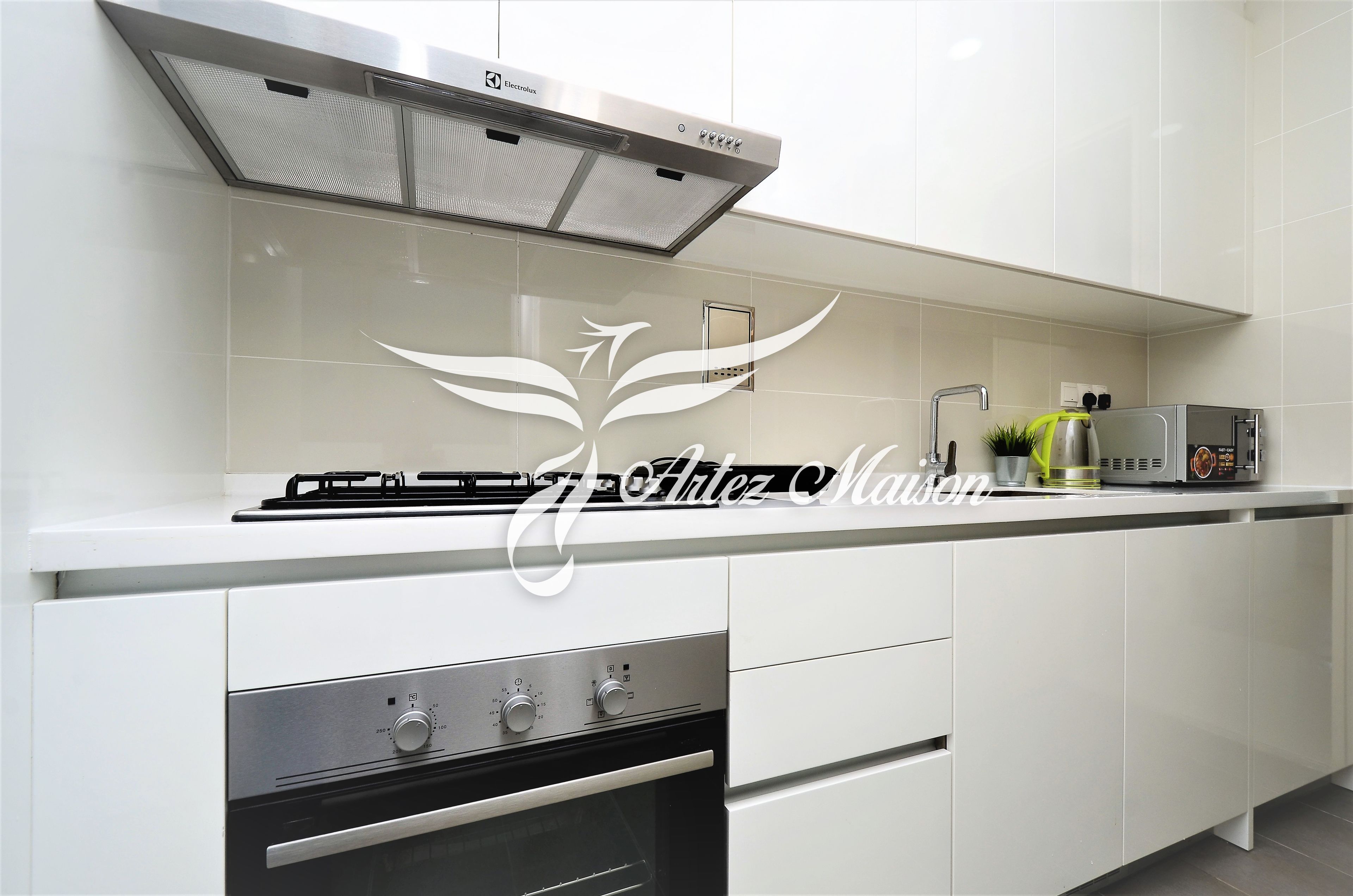 A modern kitchen with white cabinetry, a stainless steel range hood, and a built-in oven.