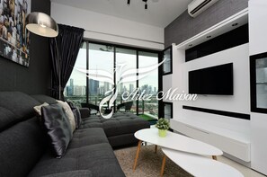 Una sala de estar moderna con un sofá grande, una mesita y un televisor montado en la pared.