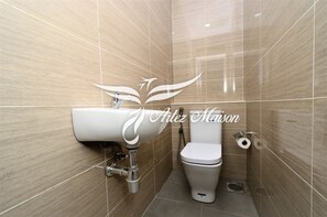 A bathroom with a white sink, toilet, and tiled walls.