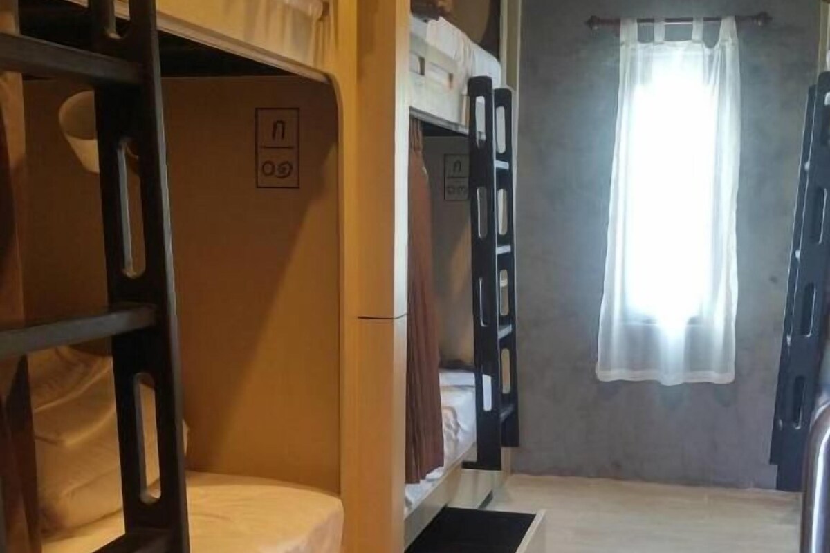 A bunk bed room with a window and a curtain.
